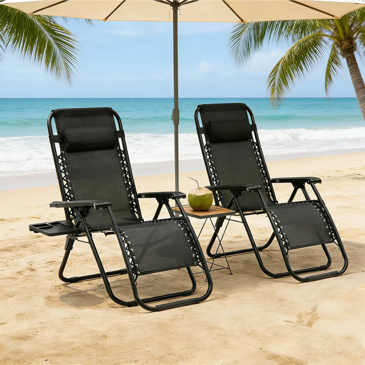 Two black zero-gravity reclining chairs under a beach umbrella on a sandy beach