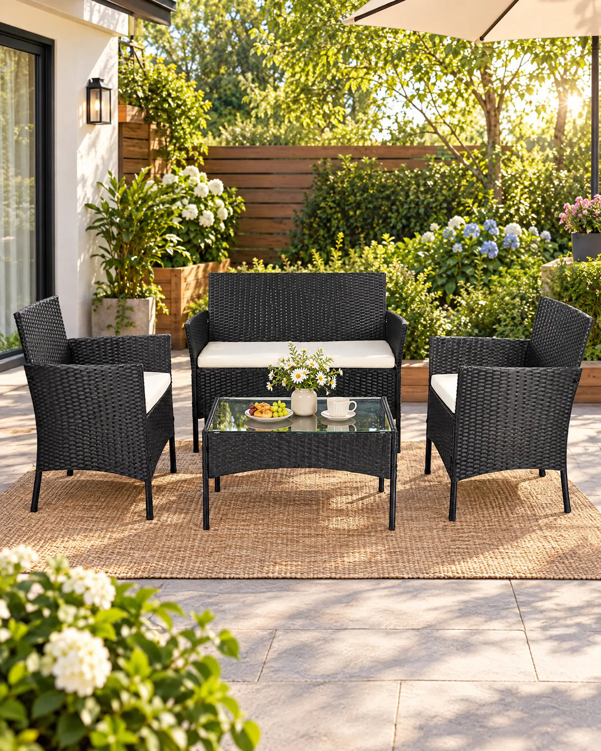Black rattan garden sofa set with cream cushions styled on a sunny garden patio
