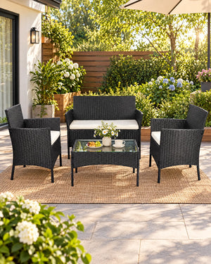 Black rattan garden sofa set with cream cushions styled on a sunny garden patio